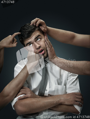 Image of A young man surrounded by hands like his own thoughts