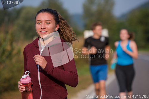 Image of young people jogging on country road