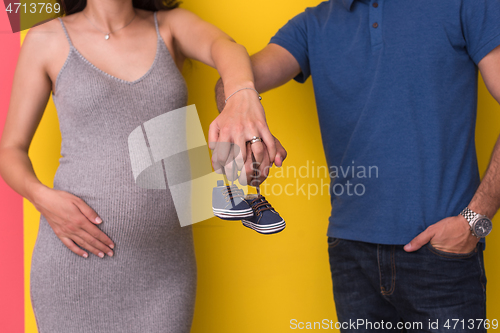 Image of couple holding newborn baby shoes