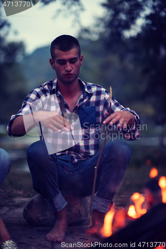 Image of young friends relaxing around campfire