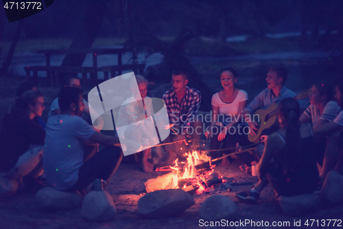 Image of young friends relaxing around campfire