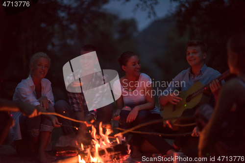 Image of young friends relaxing around campfire