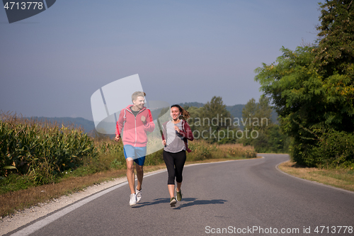 Image of young couple jogging along a country road