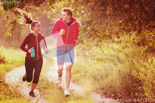 Image of young couple jogging along a country road