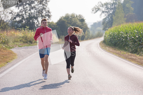 Image of young couple jogging along a country road