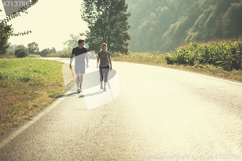 Image of young couple jogging along a country road