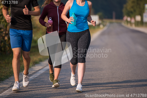 Image of young people jogging on country road