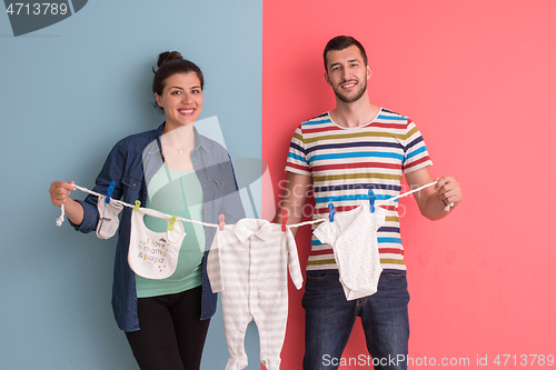 Image of young couple holding baby bodysuits