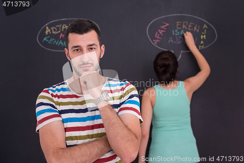 Image of pregnant couple writing on a black chalkboard