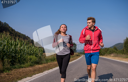 Image of young couple jogging along a country road