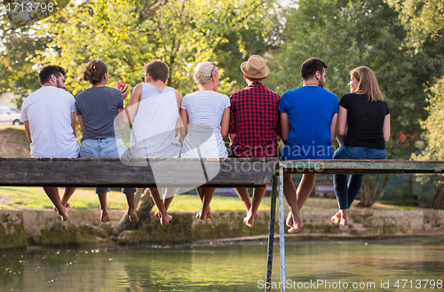 Image of rear view of friends enjoying watermelon while sitting on the wo