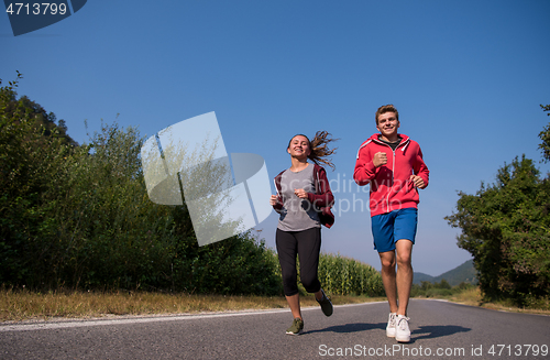 Image of young couple jogging along a country road