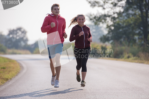 Image of young couple jogging along a country road