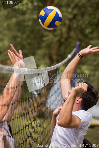 Image of group of young friends playing Beach volleyball