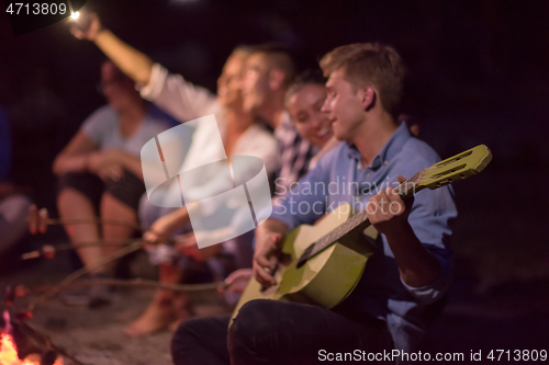 Image of young friends relaxing around campfire