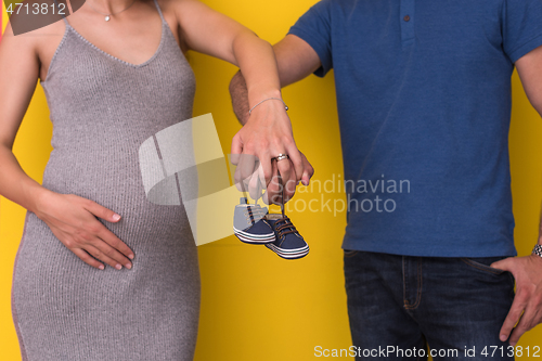 Image of couple holding newborn baby shoes