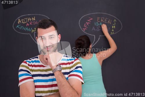 Image of pregnant couple writing on a black chalkboard