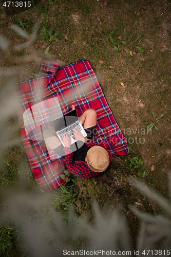 Image of top view of man using a laptop computer under the tree