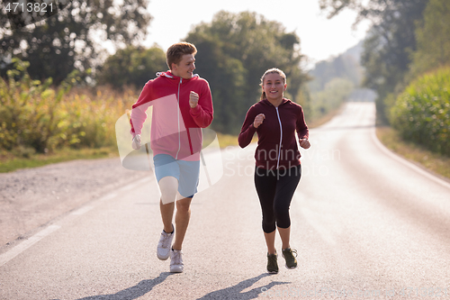 Image of young couple jogging along a country road