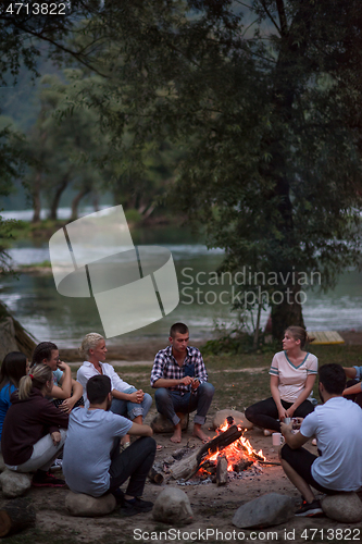 Image of young friends relaxing around campfire