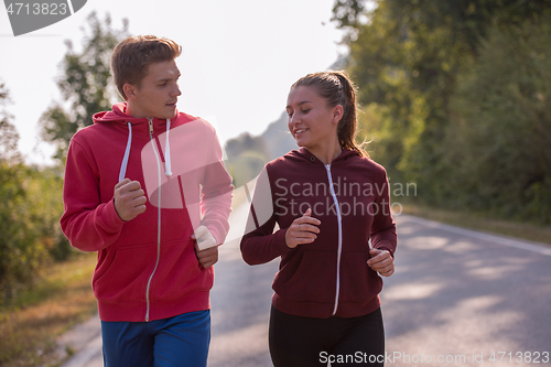 Image of young couple jogging along a country road