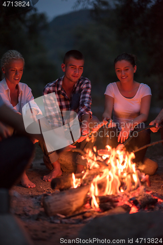 Image of young friends relaxing around campfire