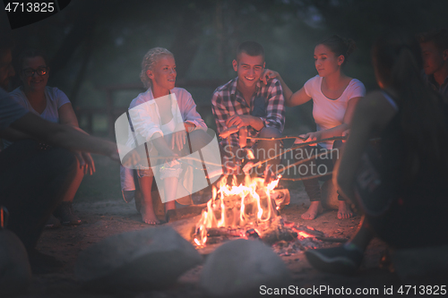 Image of young friends relaxing around campfire