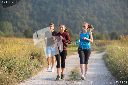 Image of young people jogging on country road