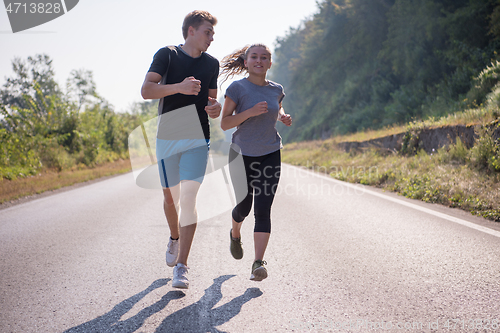 Image of young couple jogging along a country road