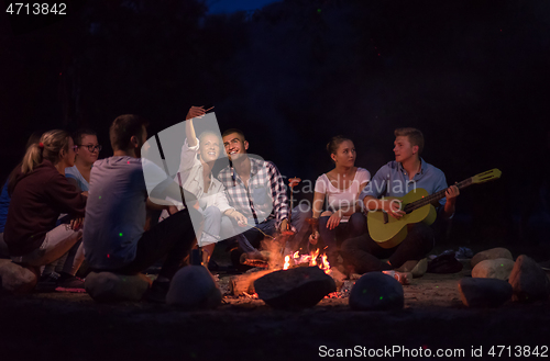 Image of young friends relaxing around campfire