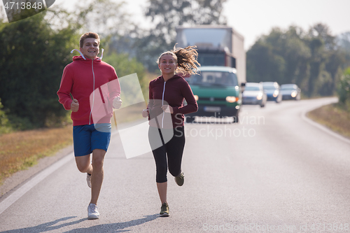Image of young couple jogging along a country road