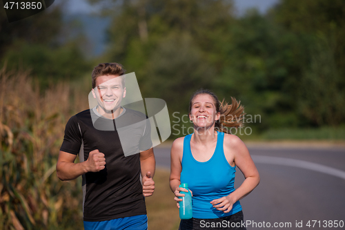 Image of young couple jogging along a country road