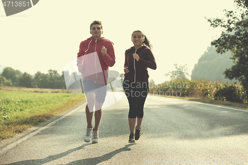 Image of young couple jogging along a country road