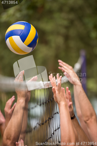 Image of group of young friends playing Beach volleyball