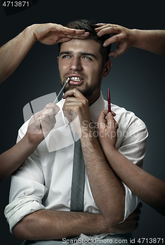 Image of A young man surrounded by hands like his own thoughts