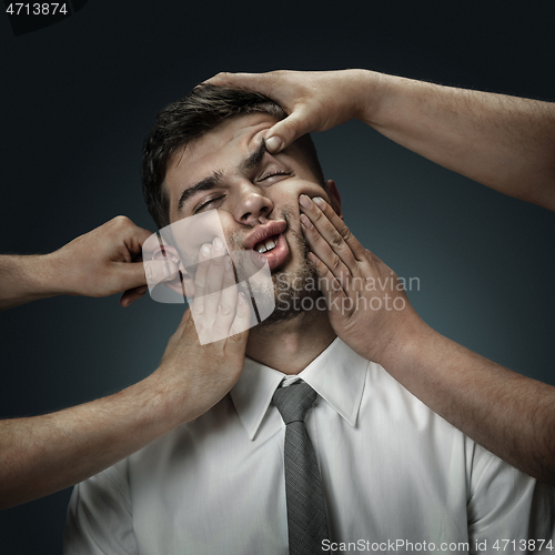 Image of A young man surrounded by hands like his own thoughts