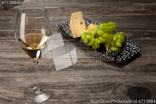 Image of A bottle and a glass of white wine with fruits over wooden background