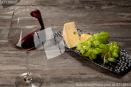 Image of A bottle and a glass of red wine with fruits over wooden background