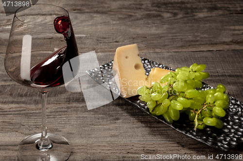 Image of A bottle and a glass of red wine with fruits over wooden background