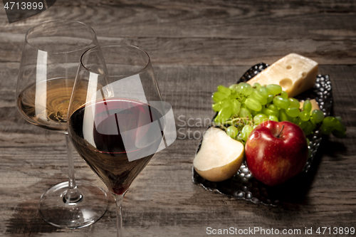 Image of A bottle and glasses of red and white wine with fruits