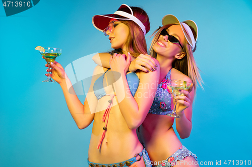 Image of Beautiful girls isolated on blue studio background in neon light