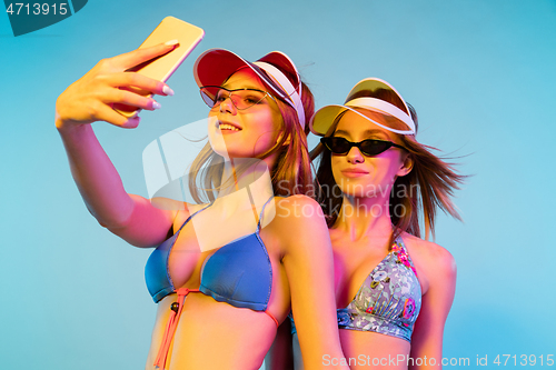 Image of Beautiful girls isolated on blue studio background in neon light