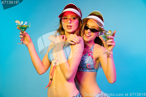 Image of Beautiful girls isolated on blue studio background in neon light
