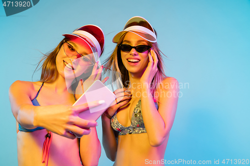 Image of Beautiful girls isolated on blue studio background in neon light