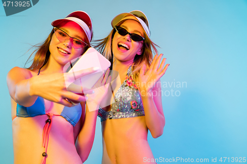 Image of Beautiful girls isolated on blue studio background in neon light