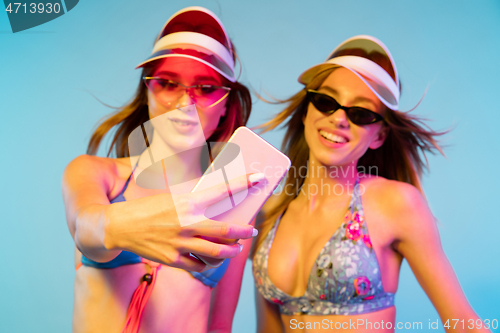 Image of Beautiful girls isolated on blue studio background in neon light