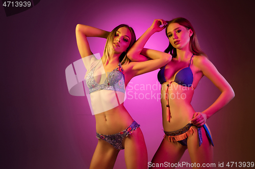 Image of Half-length portrait of two beautiful girls dancing in colorful neon light