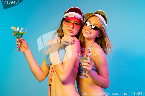 Image of Beautiful girls isolated on blue studio background in neon light