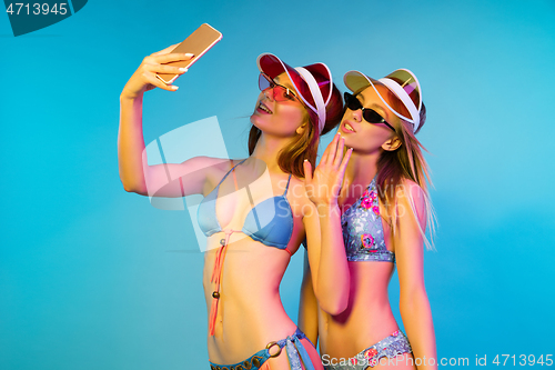 Image of Beautiful girls isolated on blue studio background in neon light