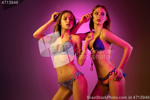 Image of Half-length portrait of two beautiful girls dancing in colorful neon light